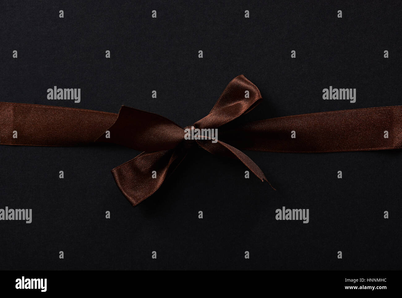 Brown silk bow ribbon  with knot on paper dark background Stock Photo