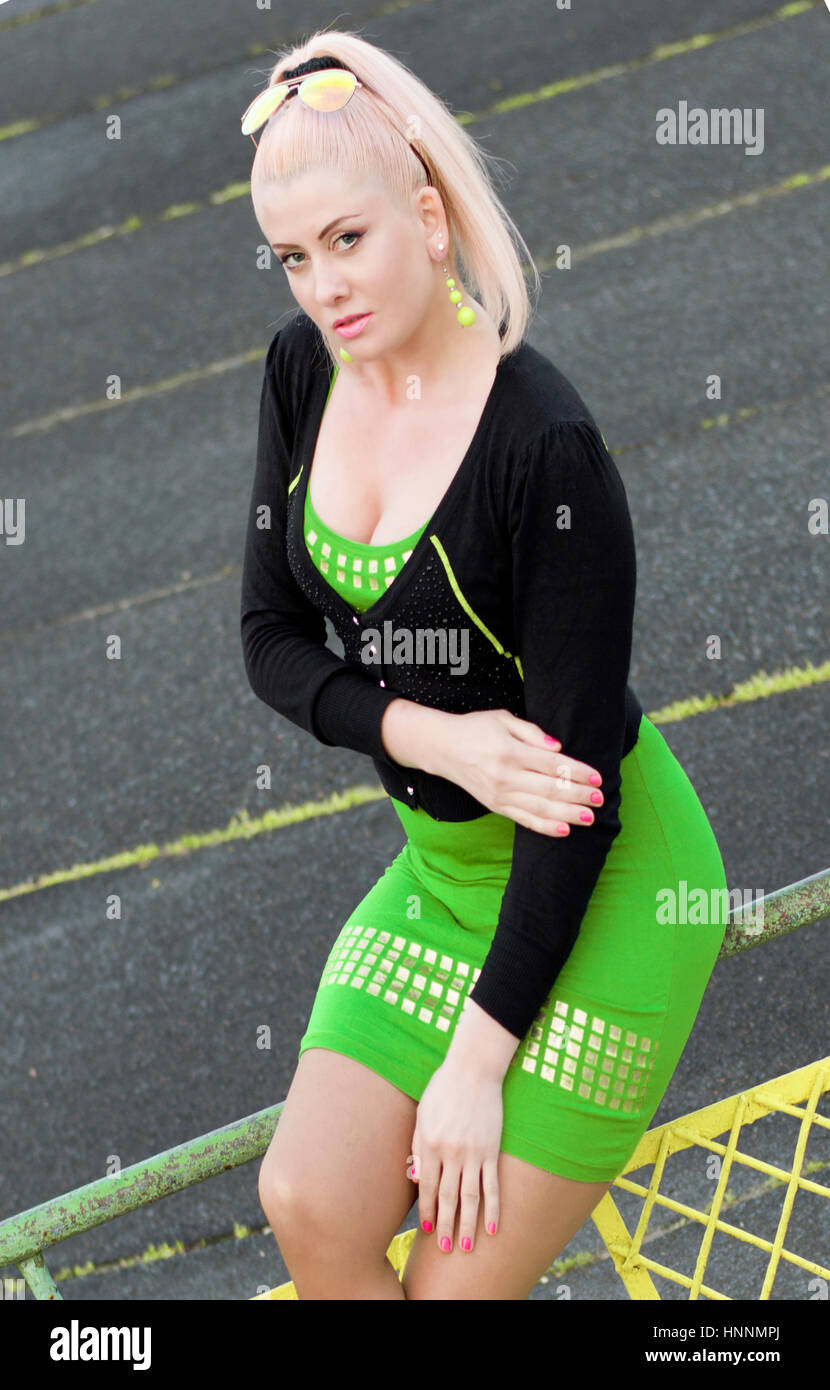 the woman in green sits on a protection at a racetrack, a subject beautiful women Stock Photo