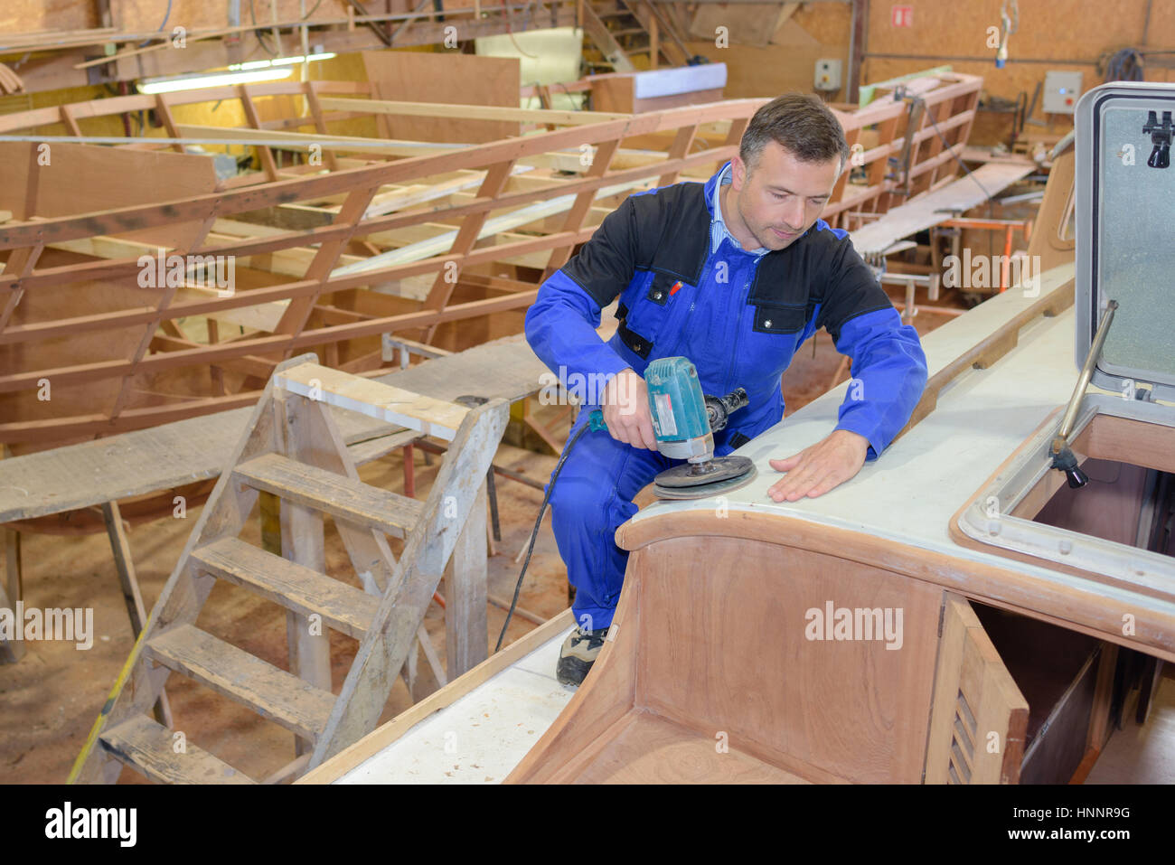 Man using sander on wooden boat Stock Photo Alamy