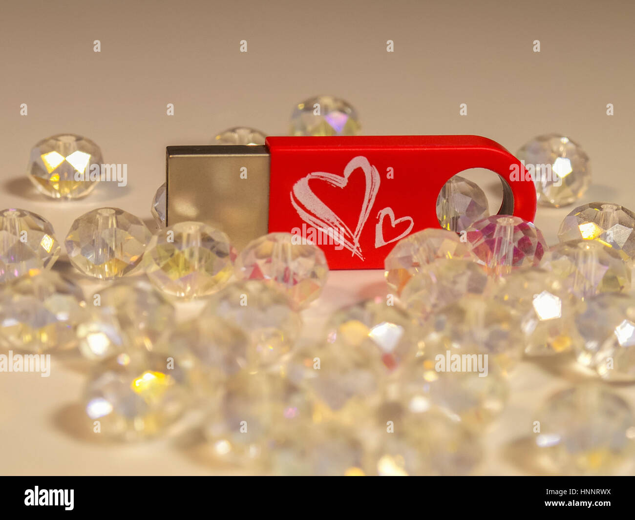 Red flash drive with heart and gems on the light background Stock Photo