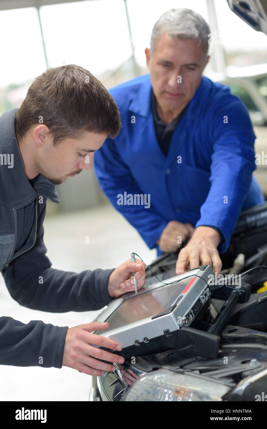 mechanic and apprentice working on car with computer Stock Photo - Alamy