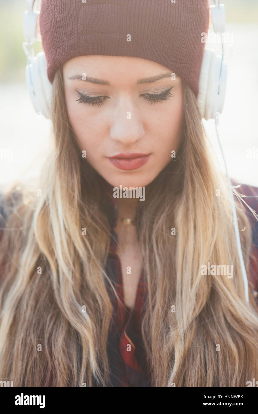Portrait of young beautiful long blonde hair womam listening music with ...
