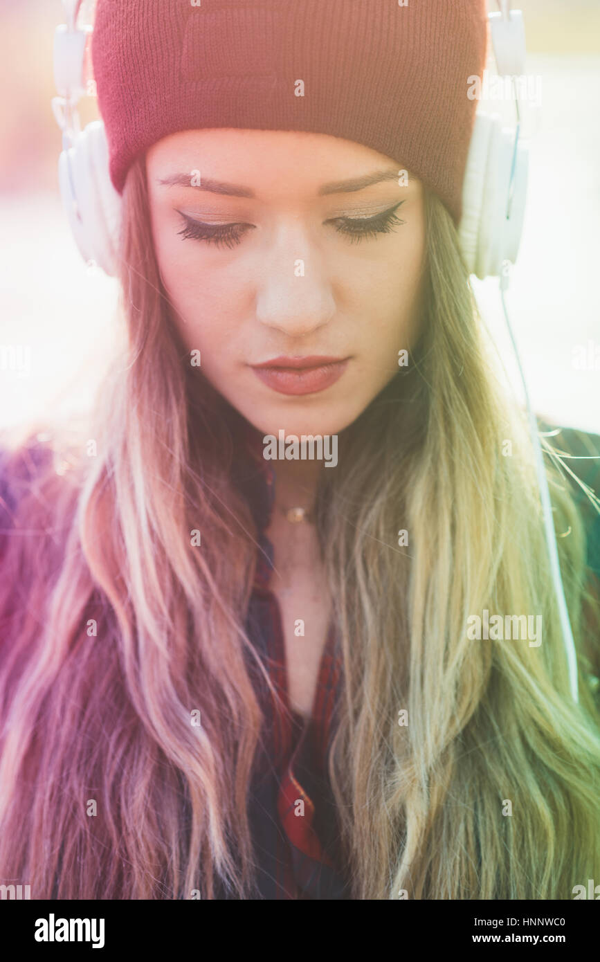 Portrait of young beautiful long blonde hair womam listening music with ...