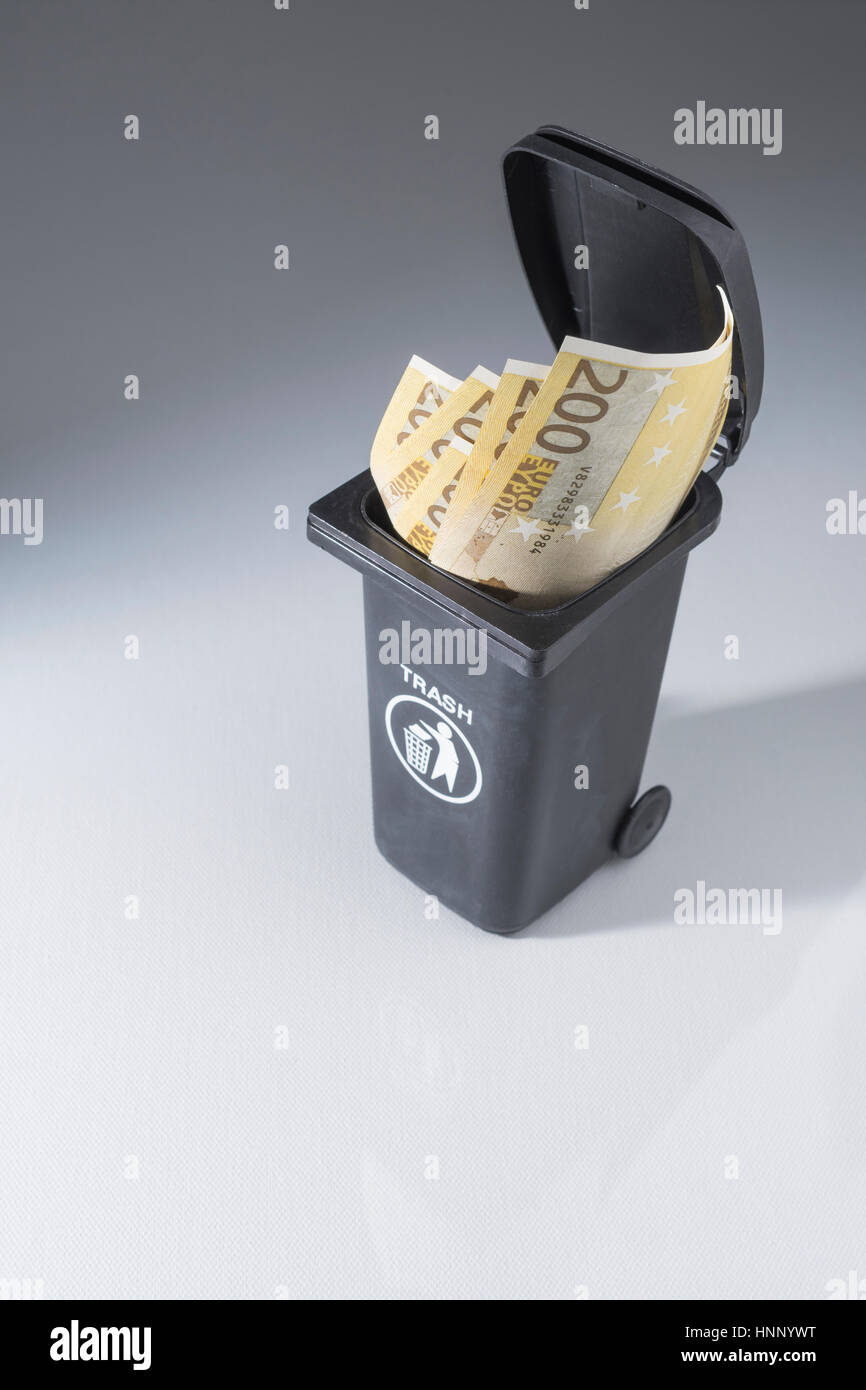 200 Euro banknotes / bills in a toy wheely bin / wheelie bin / trash bin. Metaphor for wasting money, money down the drain. Stock Photo