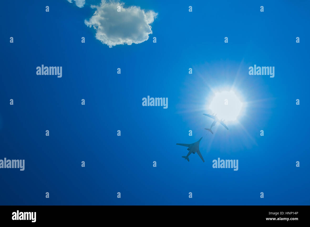 two bombers fly up through the sun on a blue sky background Stock Photo