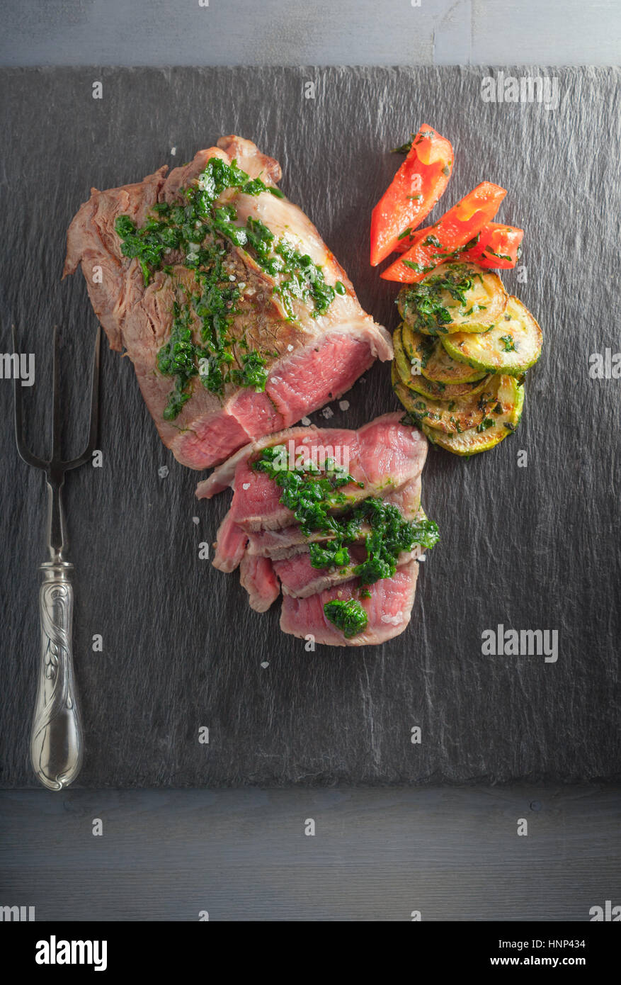 Roast Beef dinner with roasted zucchini, pepper and salsa verde Stock Photo