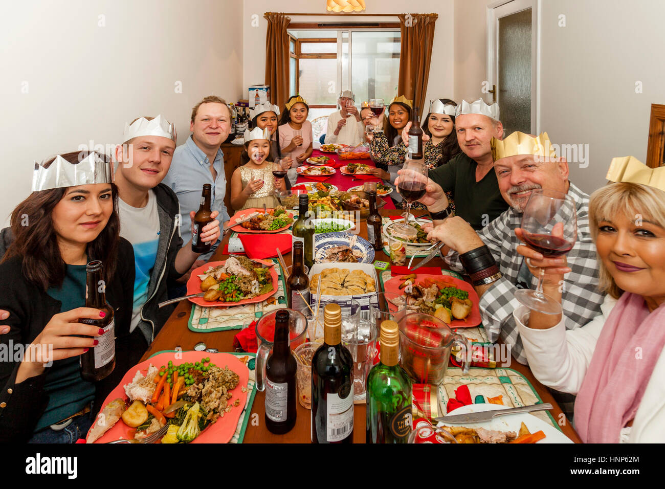A Multi Ethnic Family Sit Down To A Traditional Christmas Lunch, Sussex, UK Stock Photo
