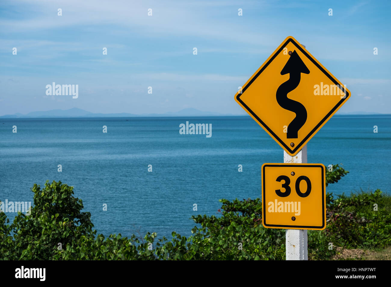 Traffic sign indicating a winding road must be using a speed of 30 kilometers per hour. Stock Photo