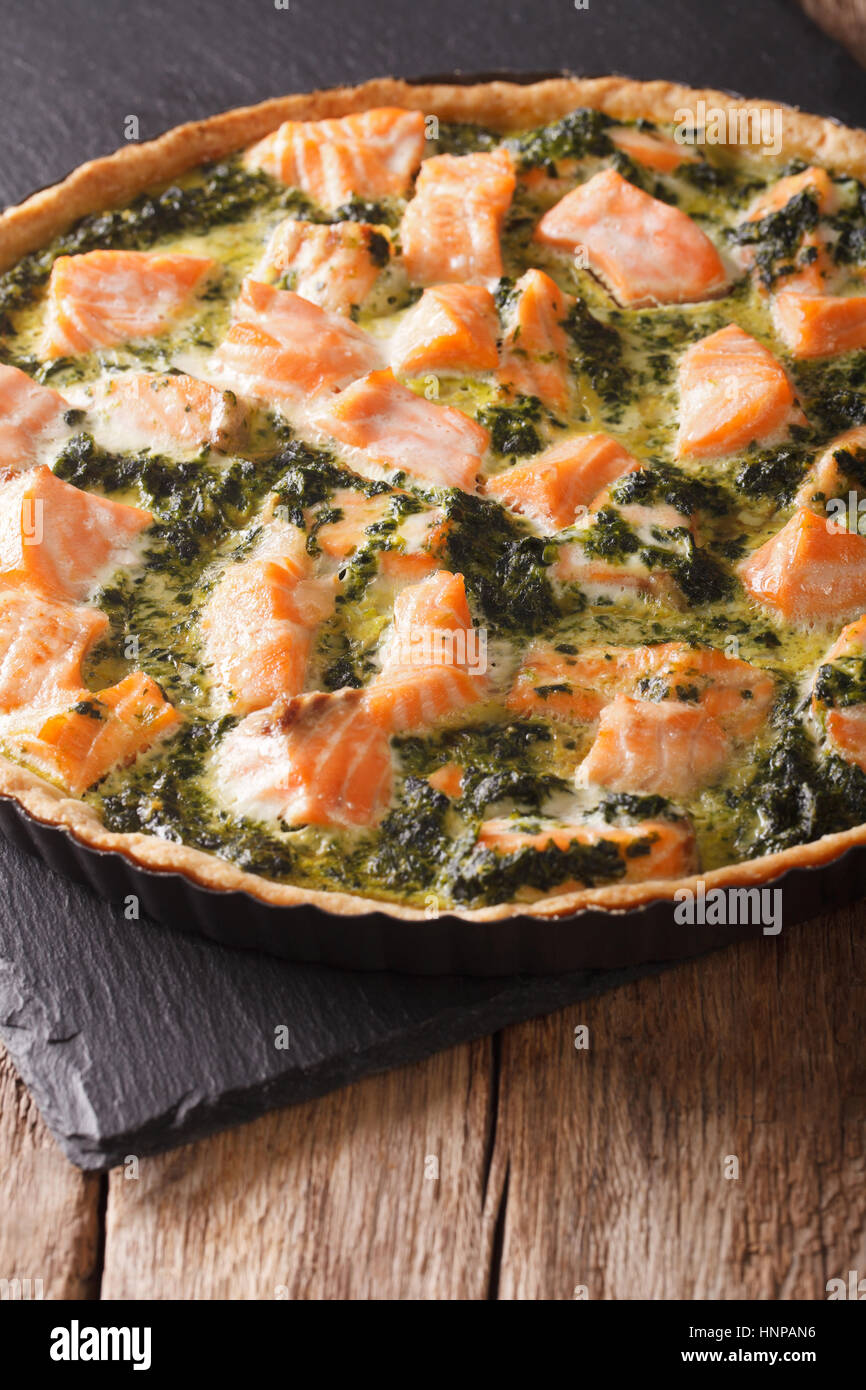 Tasty Savory Tart with salmon and spinach in the dish for baking close-up on the table. vertical Stock Photo