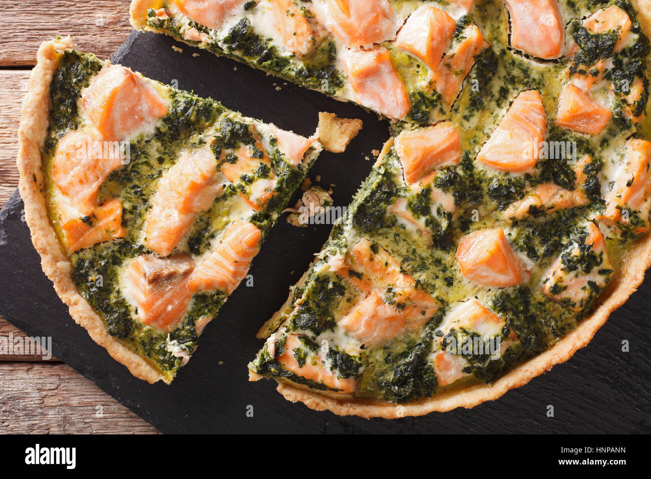 Tasty sliced Savory quiche with salmon and spinach, close-up on the table. horizontal view from above Stock Photo