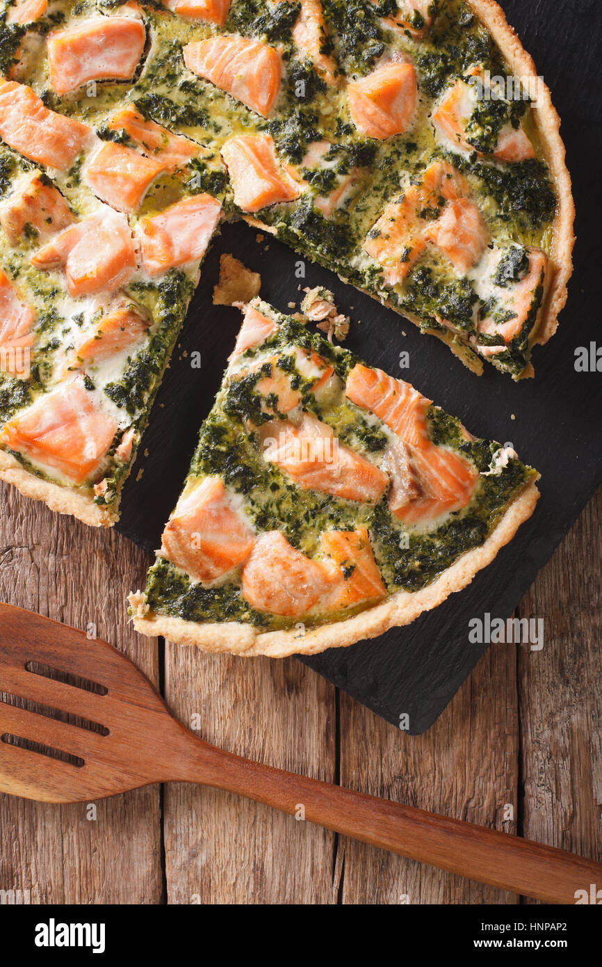 Tasty sliced Savory quiche with salmon and spinach, close-up on the table. vertical view from above Stock Photo