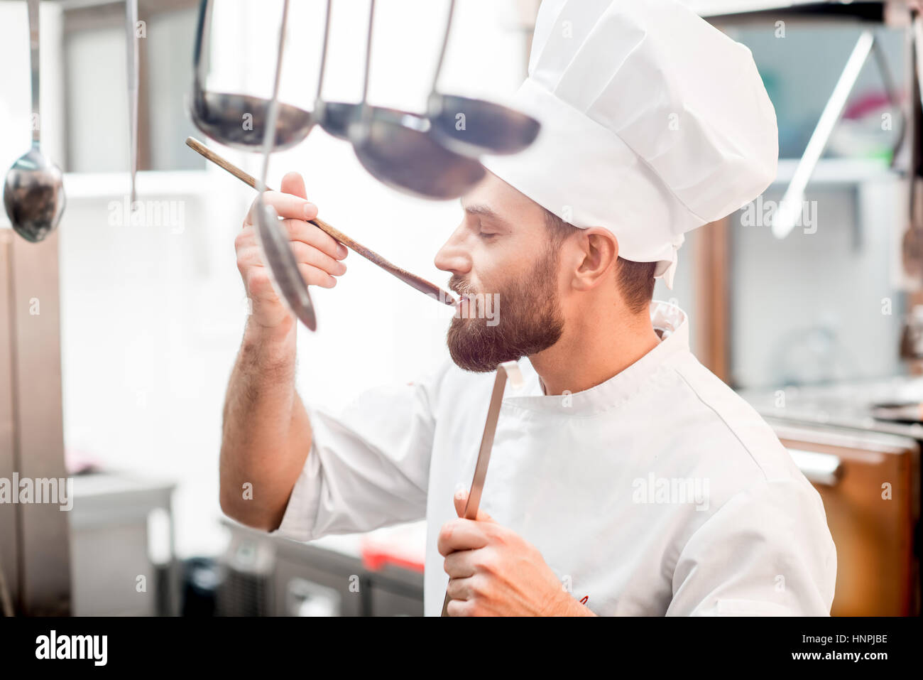 Chef cook tasting food with wooden spoon at the restaurant kitchen Stock  Photo - Alamy