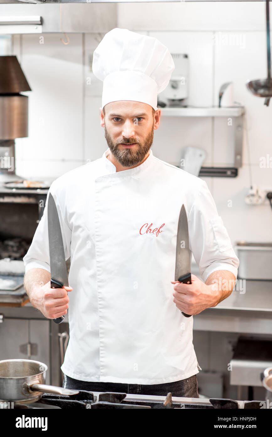 Portrait of chef cook in uniform with knifes at the restaurant kitchen Stock Photo
