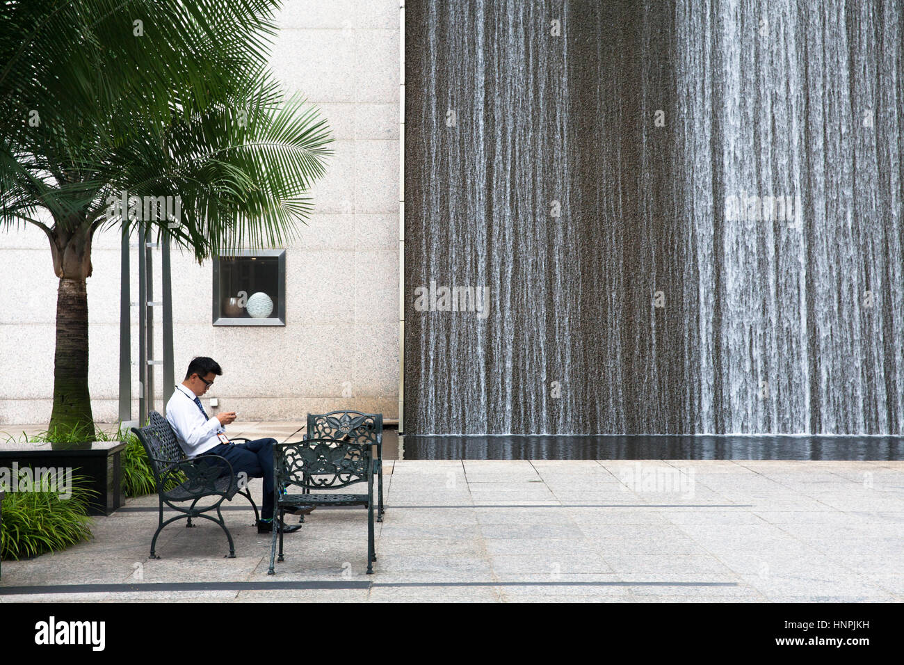 Office worker rests at the smoking area located in Central Business District on July 10, 2013 in Singapore. Stock Photo