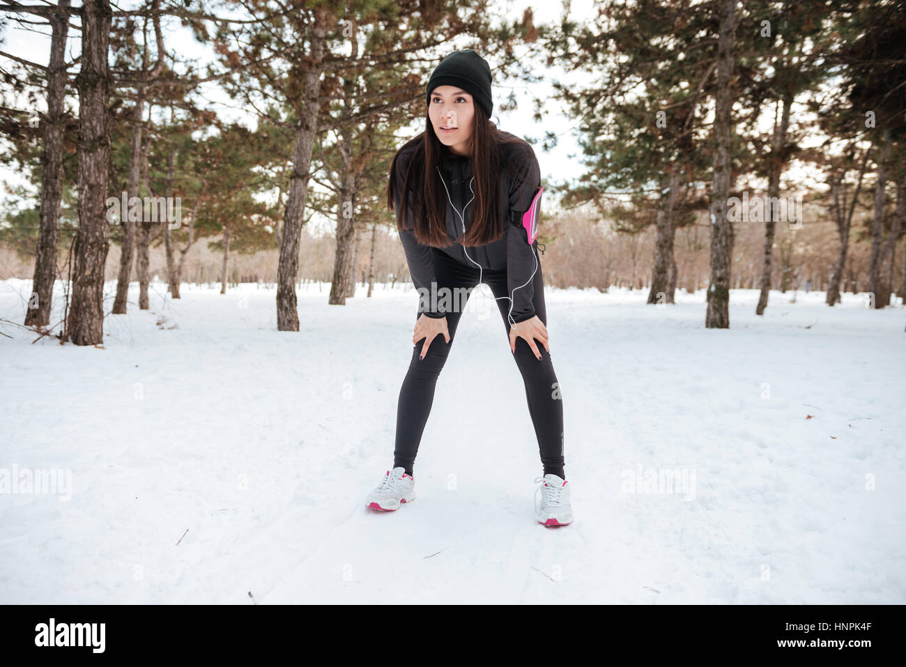 Female athlete exercising outside in cold weather on forest path wearing activewear Stock Photo