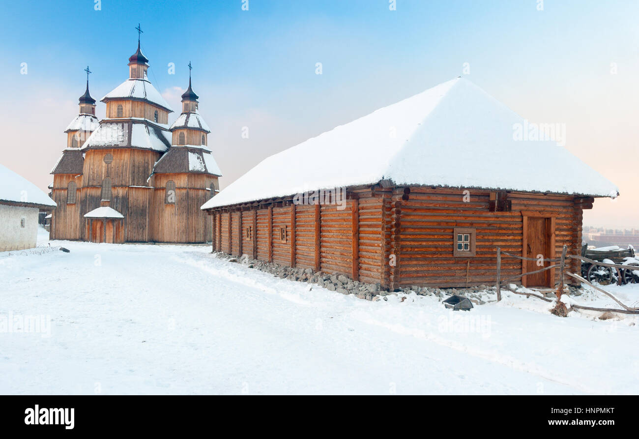 Wooden house and church on 'Zaporozhian Sich' cossacks fortress in winter with snowy roofs, Khortytsia island, Zaporozhye, Ukraine Stock Photo