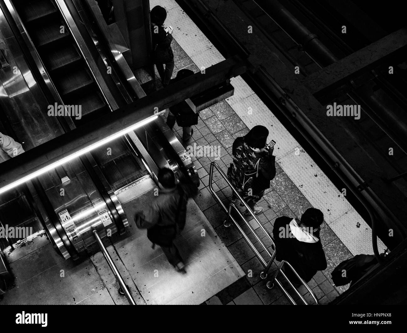 New York Subway System. Commuters use phones while they wait. Stock Photo
