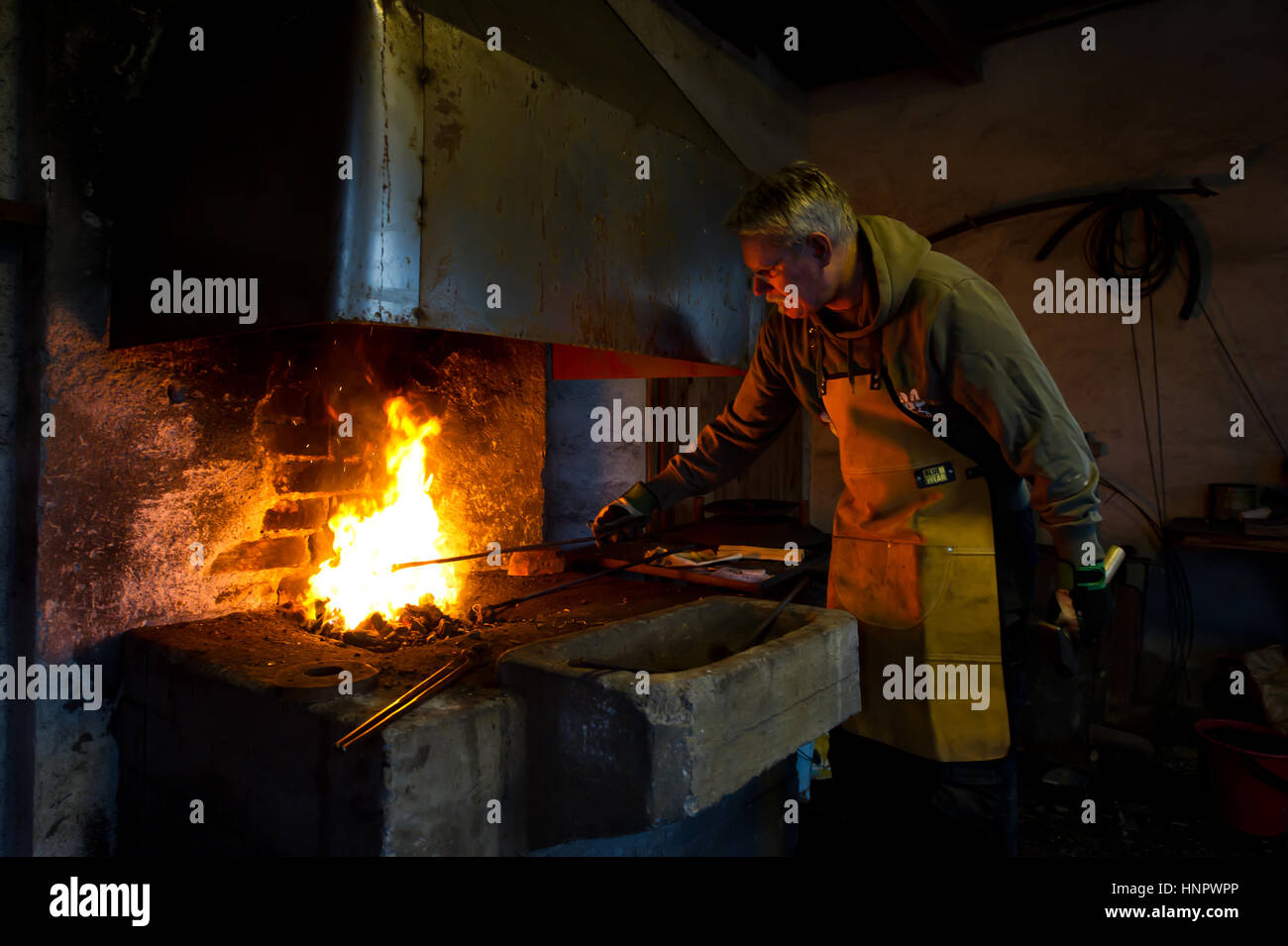 The Torresta Blacksmith heating the iron in the pit coal fire in Uppland, Sweden Stock Photo