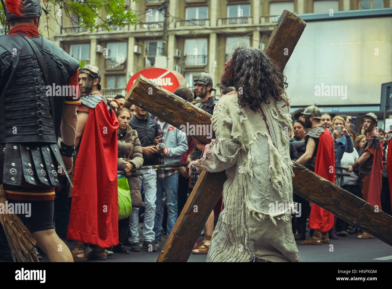 Actor plays exhausted Jesus Christ carrying large wooden cross during the reenactment of the Way of Sorrows on April 15, 2014, Bucharest, Romania Stock Photo