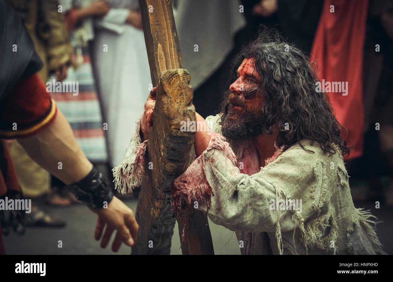 Actor plays wounded tired Jesus Christ carrying large wooden cross during the reenactment of the Way of Sorrows on April 15, 2014, Bucharest, Romania Stock Photo