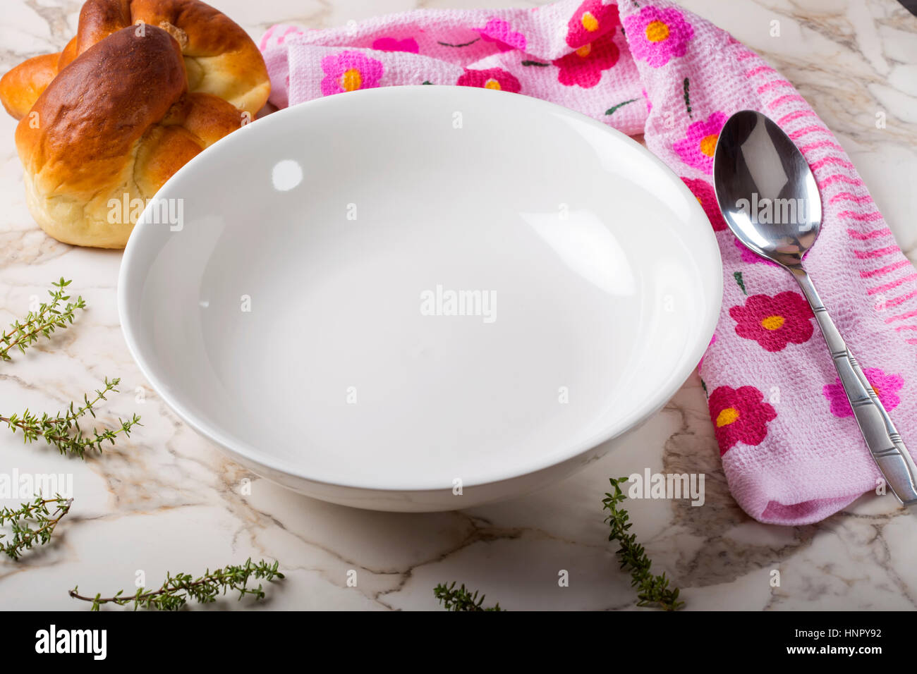 Empty plate for soup with spoon, bread and herbs on table Stock Photo