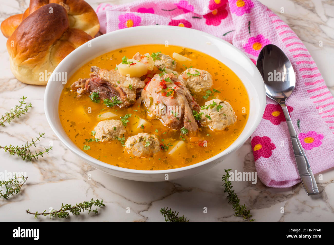 Meatballs soup with chicken meat and herbs in white bowl with spoon and bread Stock Photo