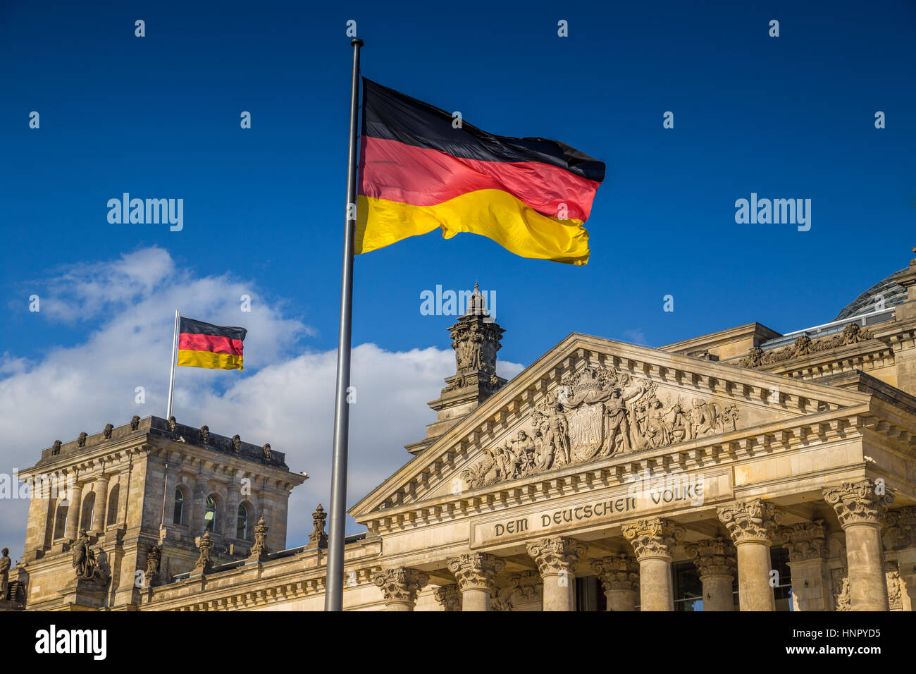 German flags waving in the wind at famous Reichstag building, seat of the German Parliament, on a sunny day with blue sky, Berlin Mitte, Germany Stock Photo