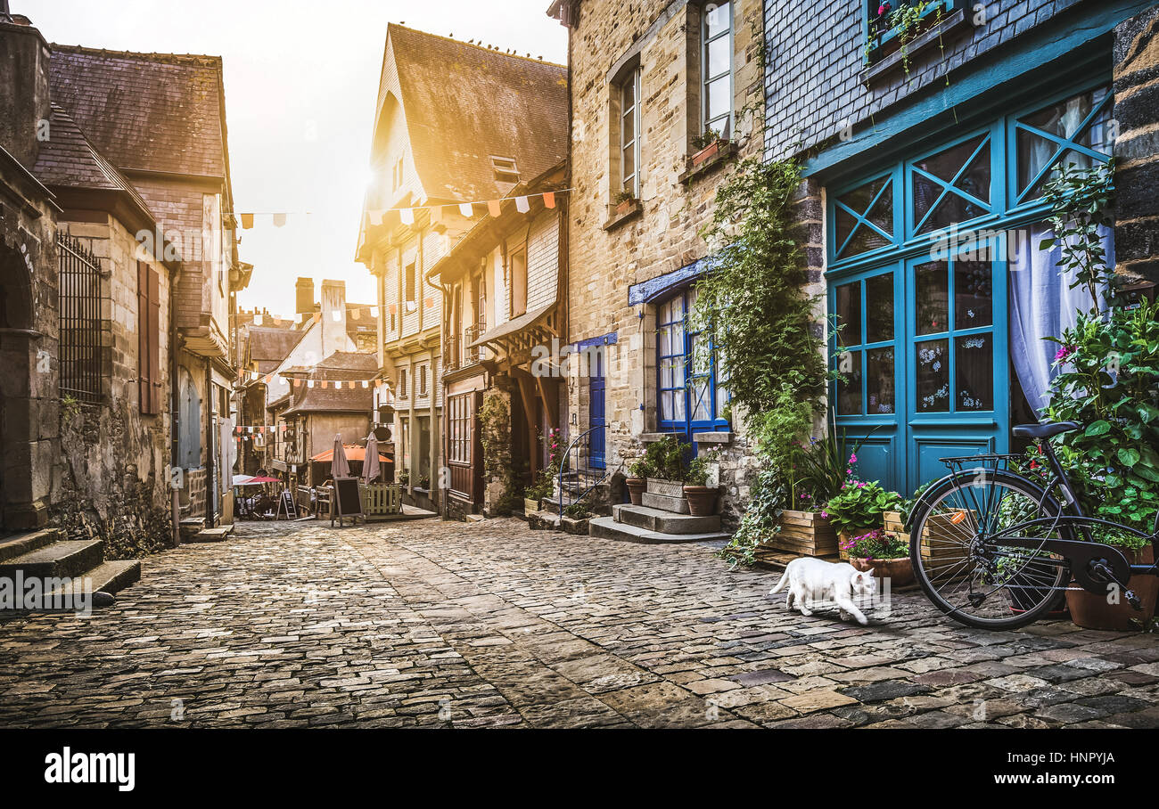 Charming street scene of an old town in Europe at sunset with retro vintage Instagram style filter and lens flare sunlight effect in summer Stock Photo