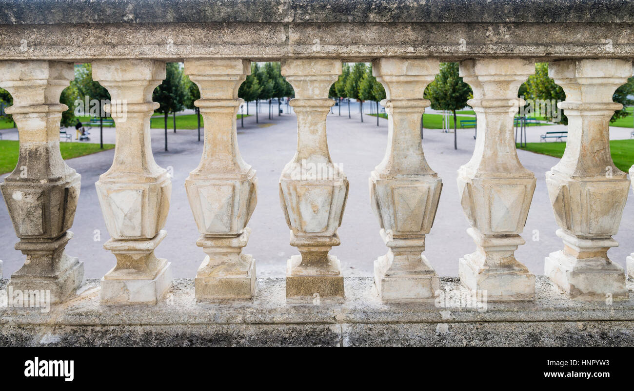 A view of a formal gardens is visible through marble balustrades. Stock Photo