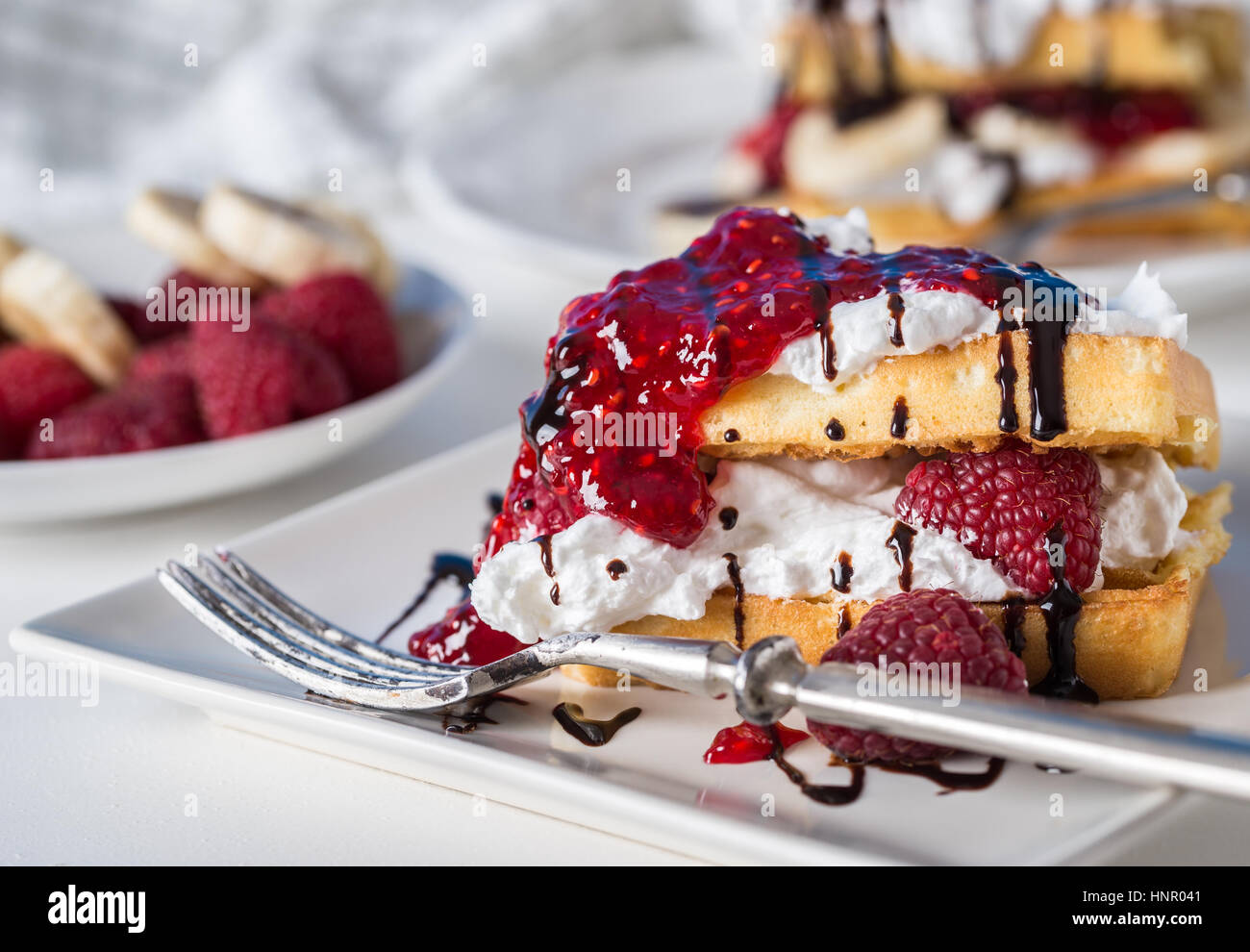 Belgian waffles with raspberries and double cream on white plate Stock