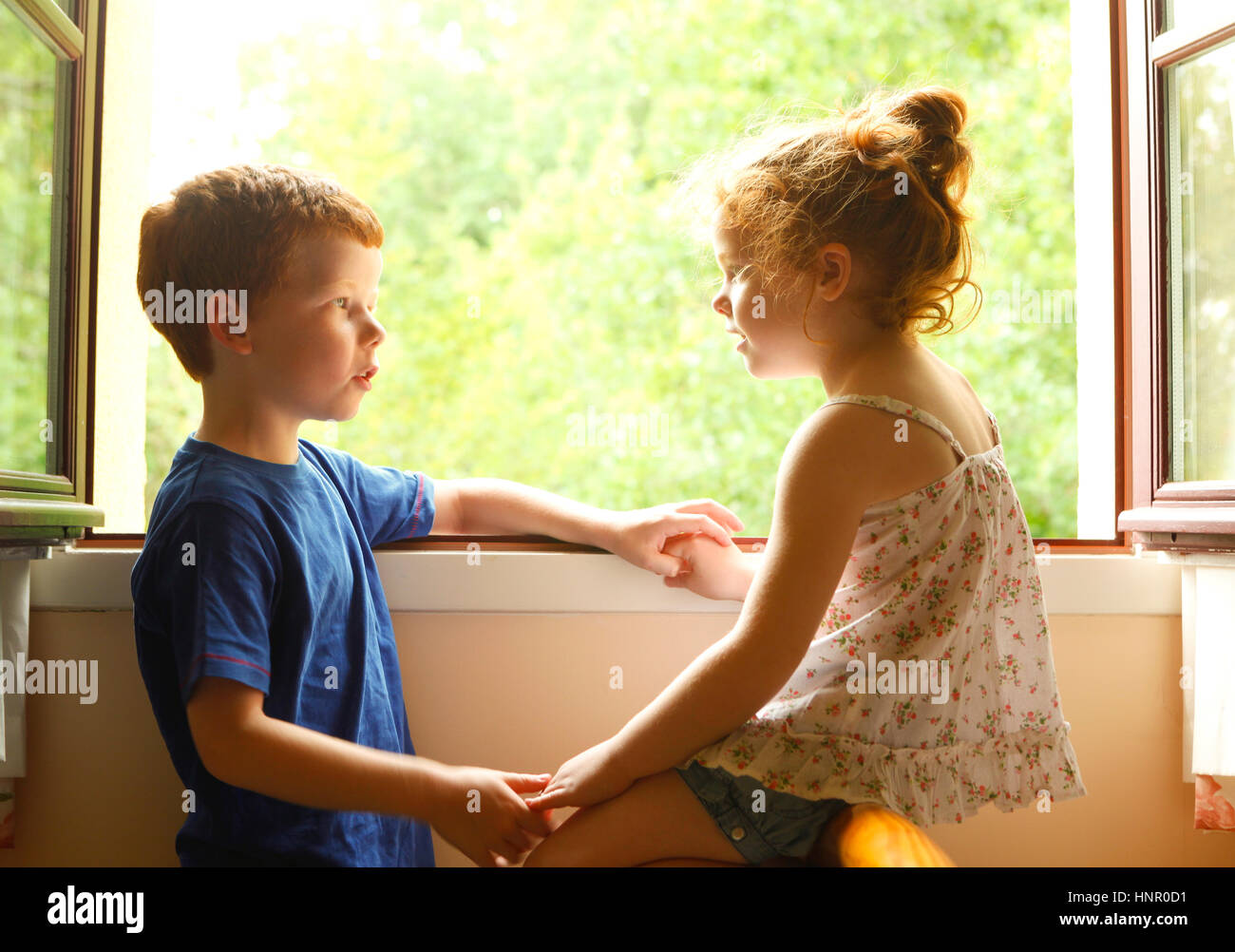 A brother and sister talking to each other by a window Stock Photo Alamy