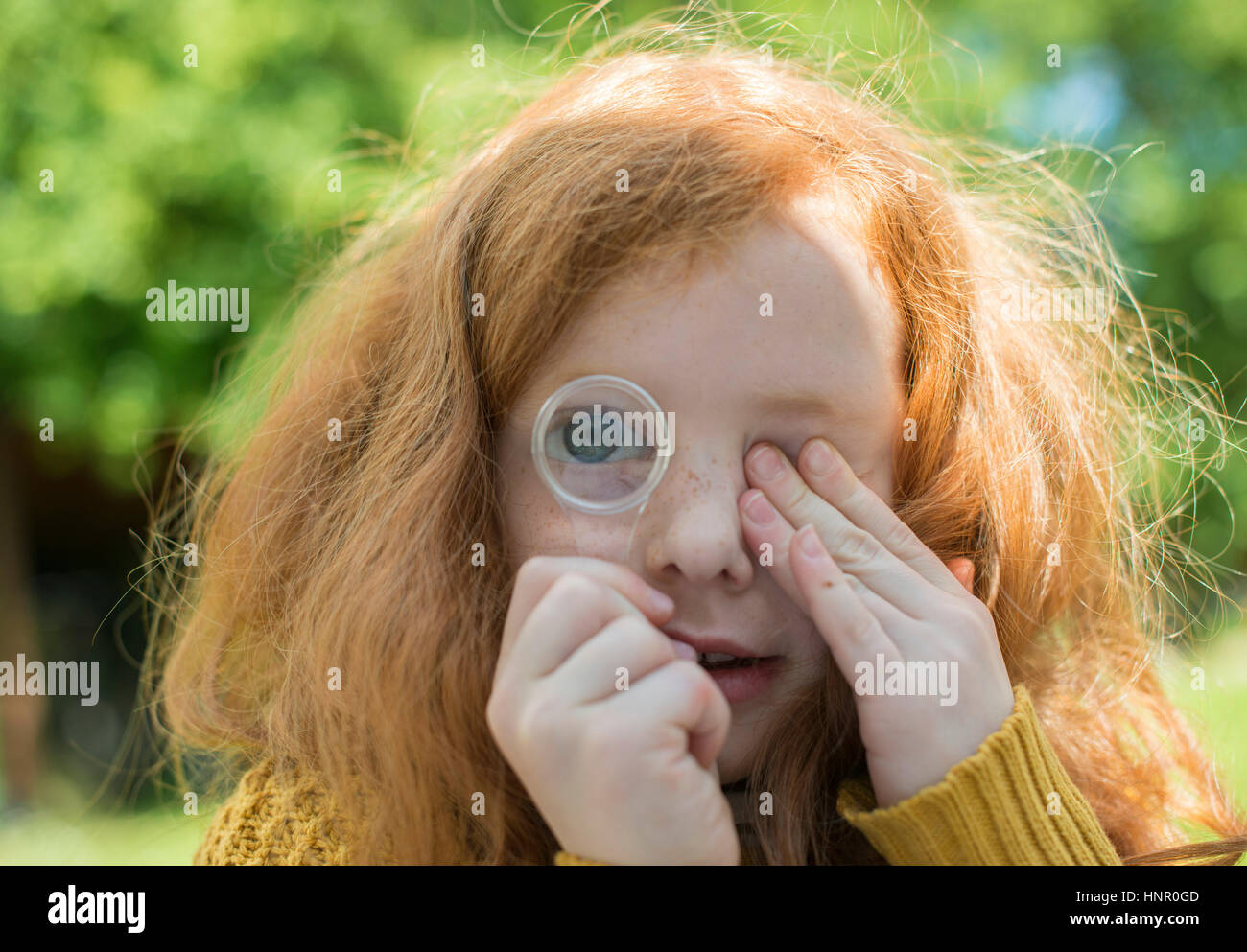 A little girl looking through a magnifying glass in her garden Stock Photo