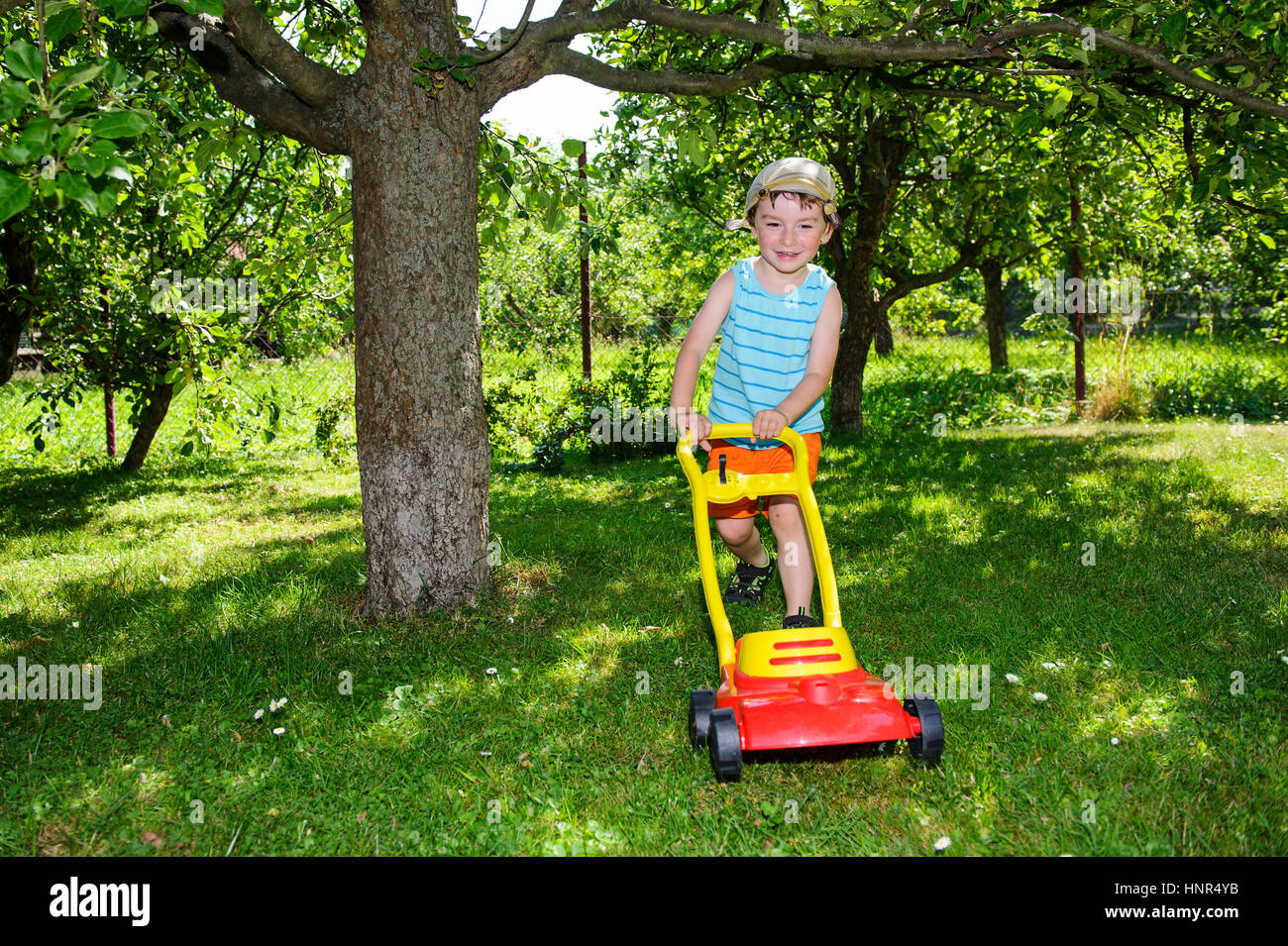 Happy small boy help with gardening with his lawn mower on sunny day with  stripped t-shirt and handkerchief with small knotts on head Stock Photo -  Alamy