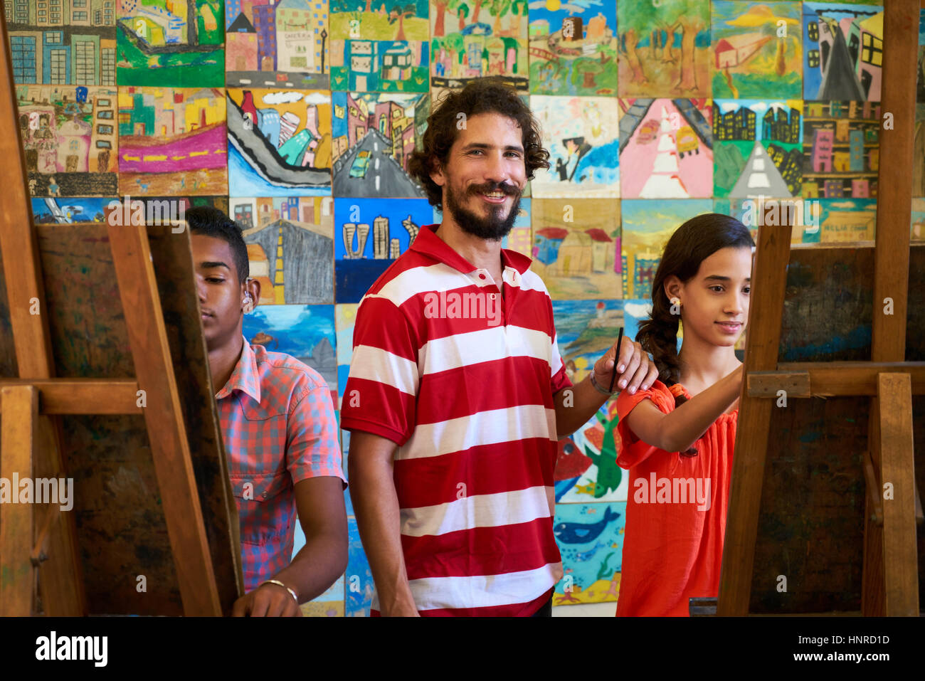 School of art, college of arts, education for group of young students. Portraif of happy latino professor smiling, man working as teacher and looking  Stock Photo