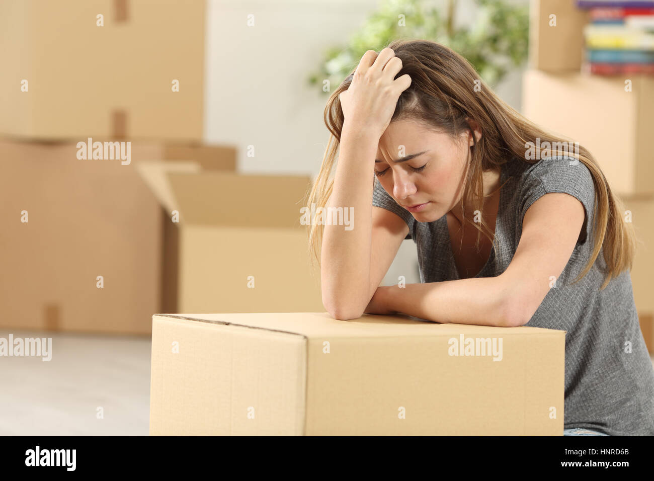 Sad homeowner moving home after eviction sitting on the floor of the living room at home Stock Photo