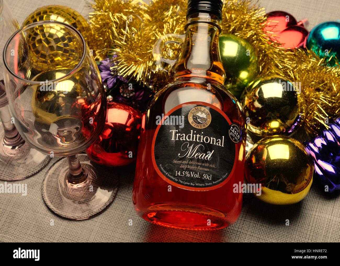 Festive image of tinsel, baubles, drinking glass and bottle of mead Stock Photo