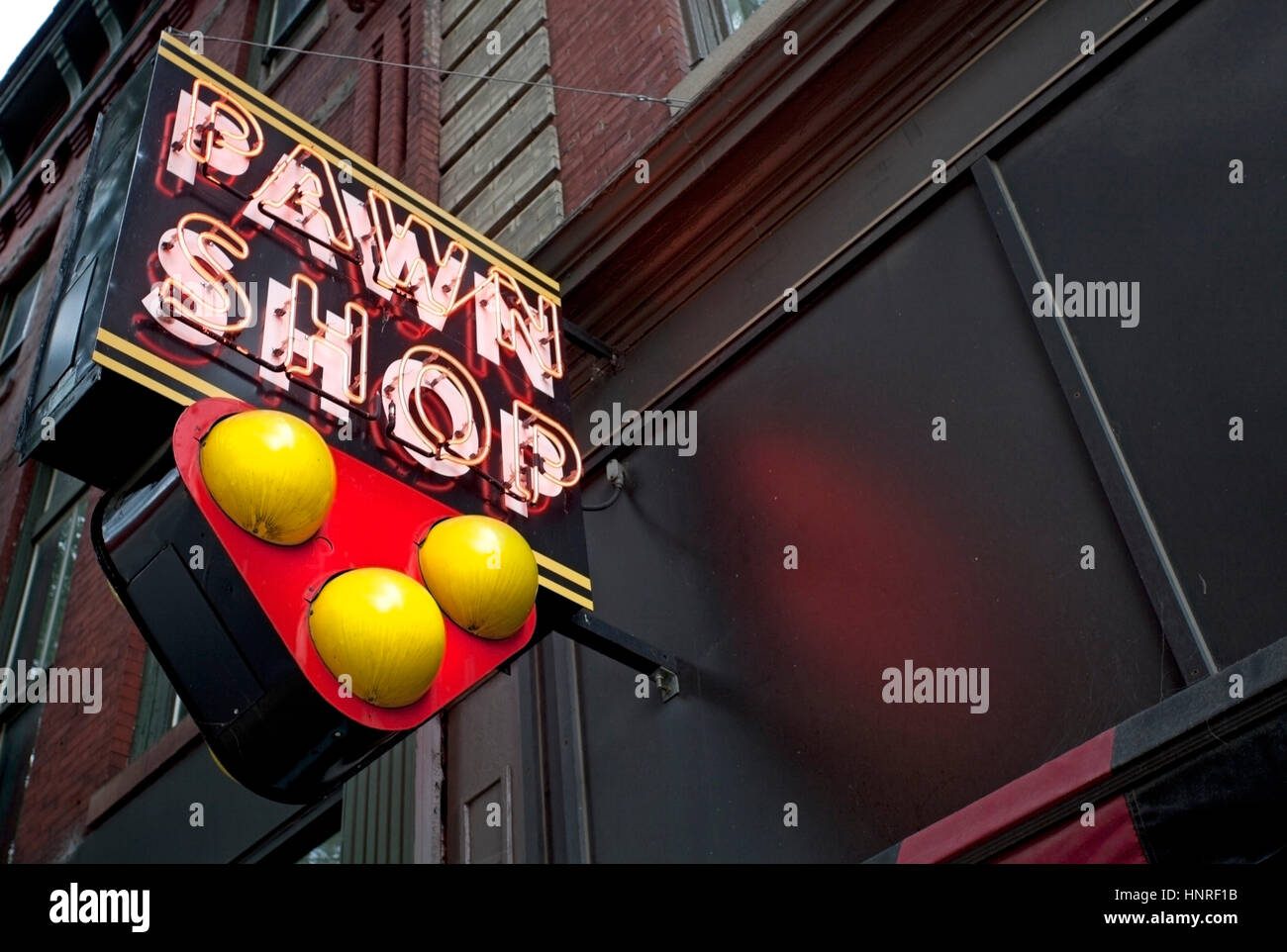 Neon PAWN SHOP sign with three balls attached to building. Stock Photo