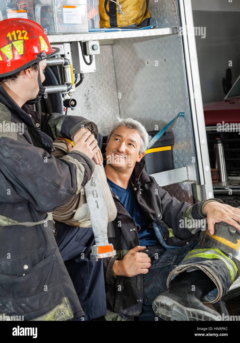 Firefighter Discussing With Colleague On Truck Stock Photo