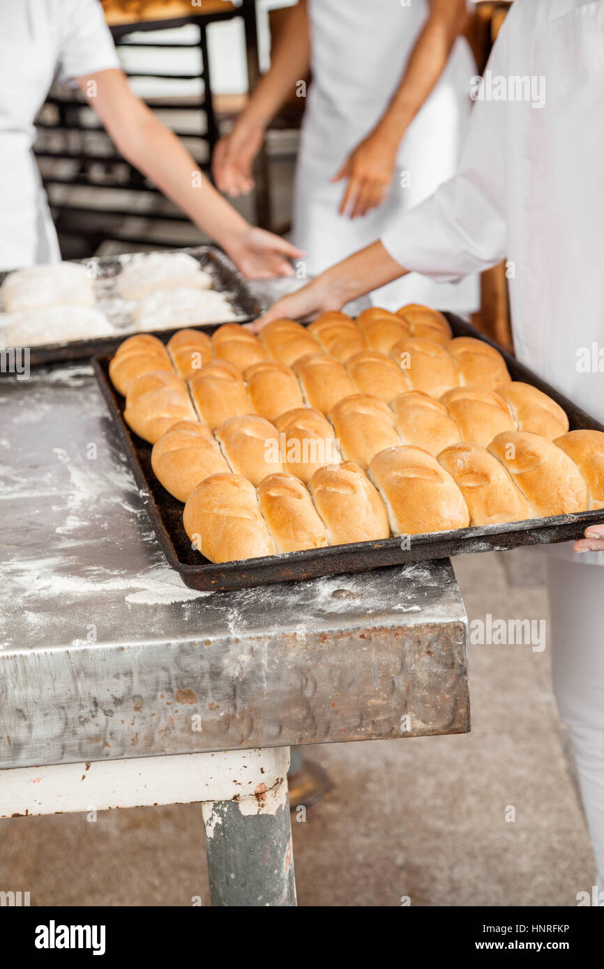Midsection Of Baker With Bread Loaves In Baking Tray Stock Photo