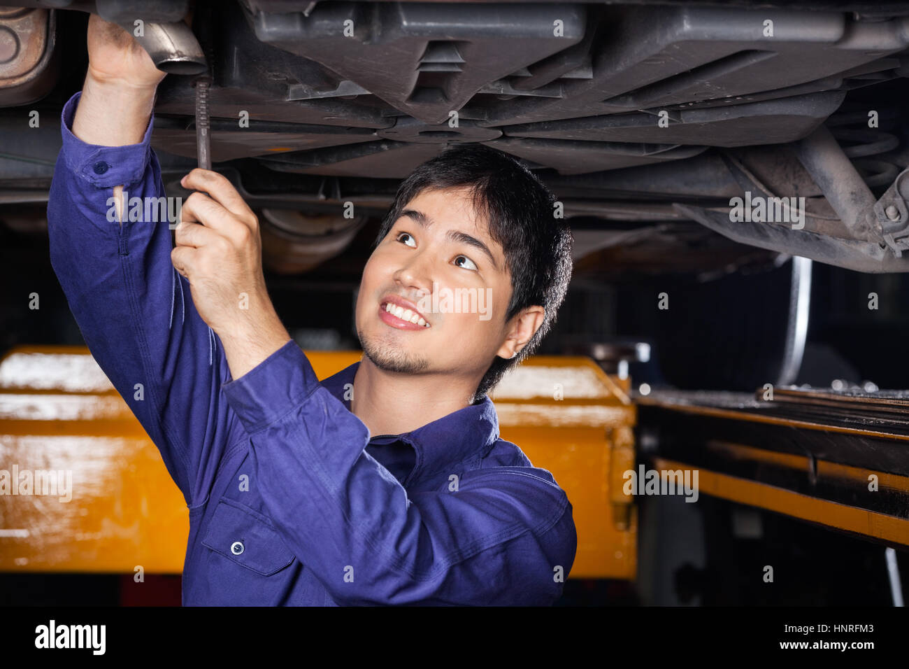 Mechanic Repairing Underneath Lifted Car Stock Photo