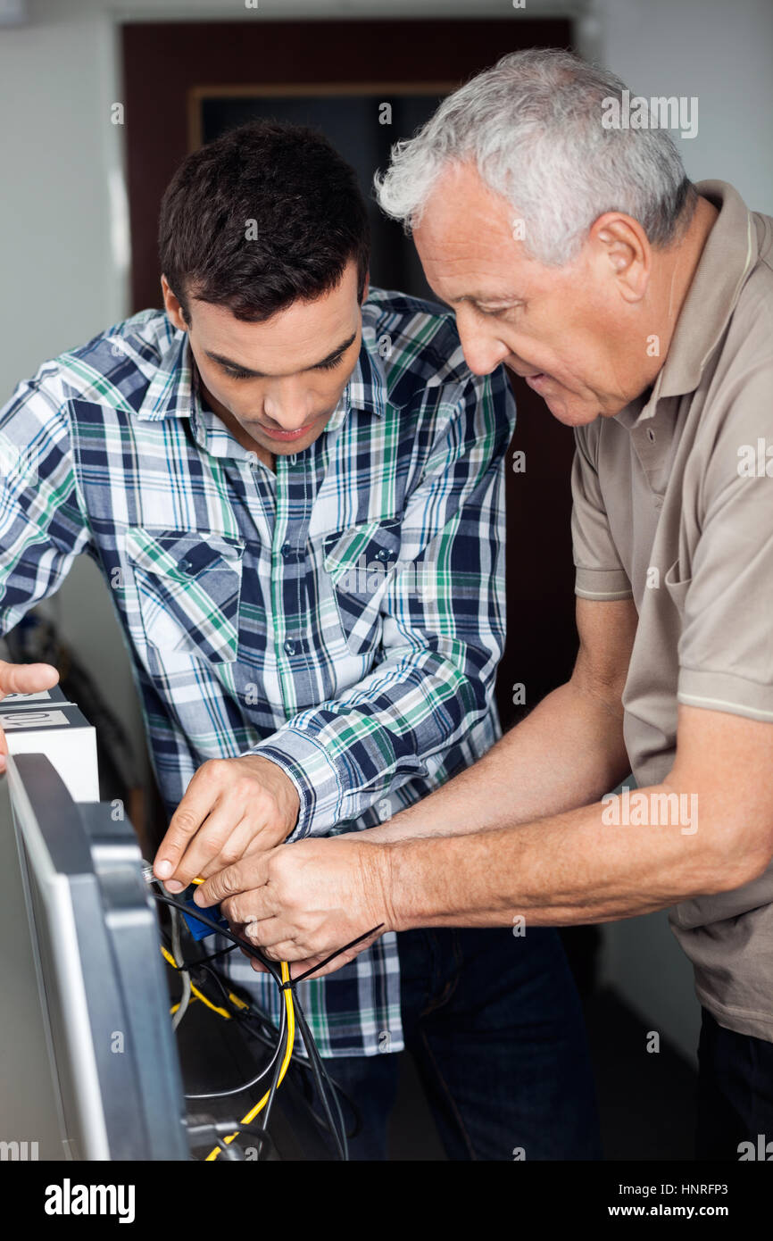 Tutor And Senior Man Fixing Computer In Class Stock Photo