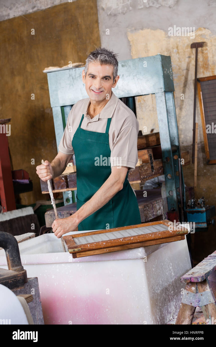 Smiling Worker Stirring Pulp And Water With Stick Stock Photo