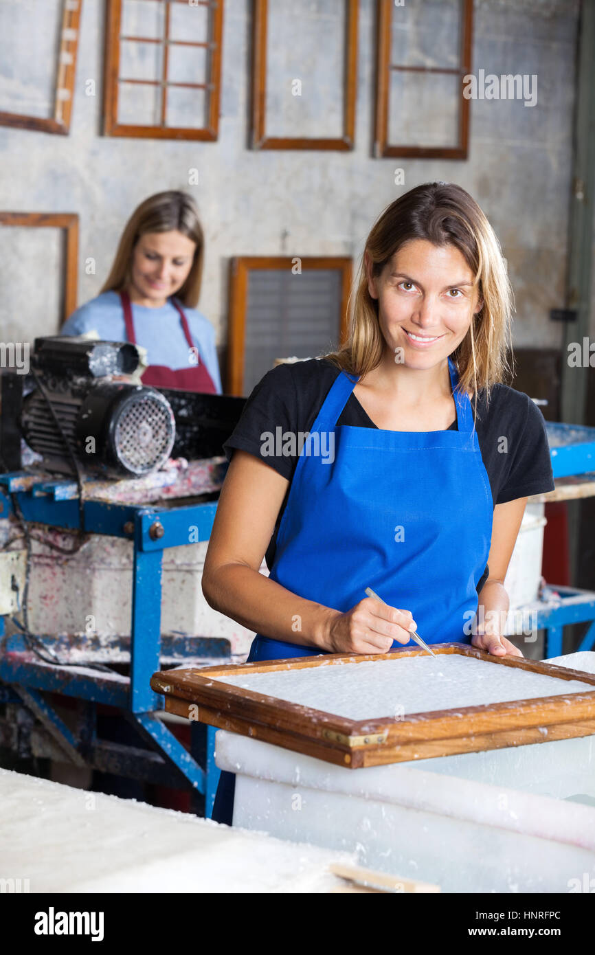 Happy Female Worker Using Tweezers To Clean Paper On Mold Stock Photo