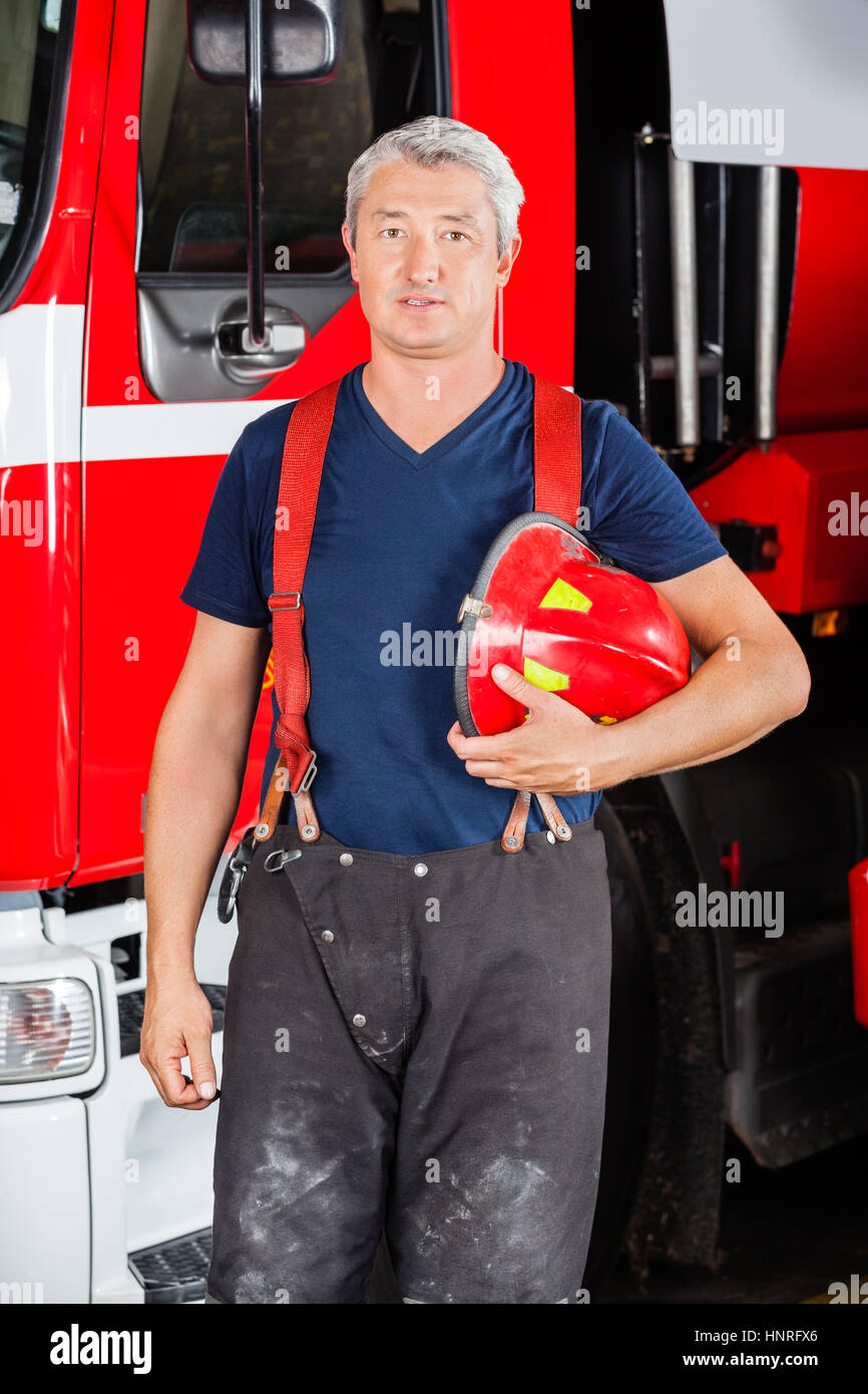 Confident Firefighter Holding Red Helmet Stock Photo