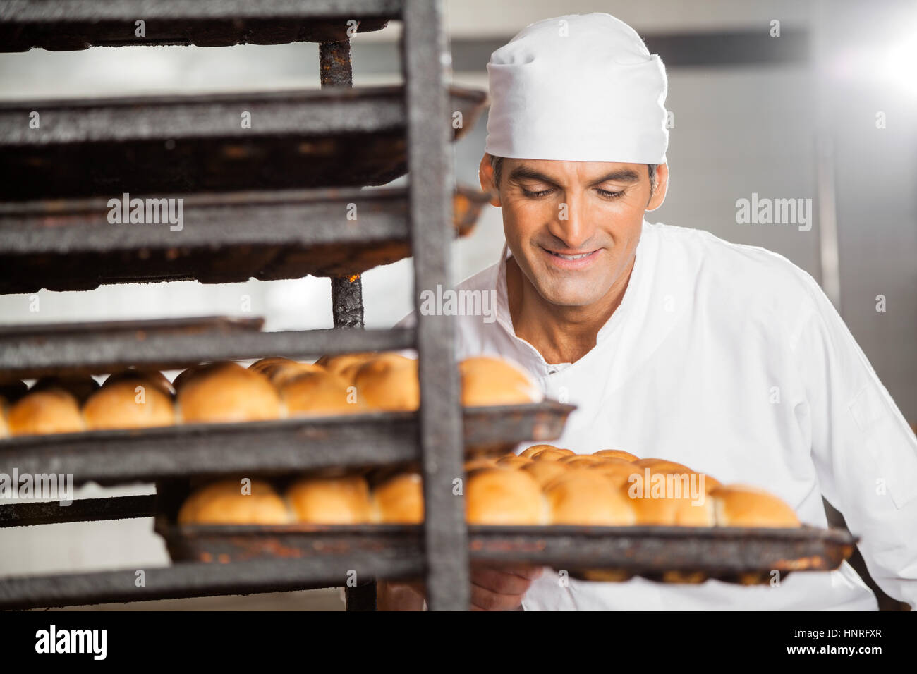 Smiling Baker Removing Baking Tray From Rack Stock Photo