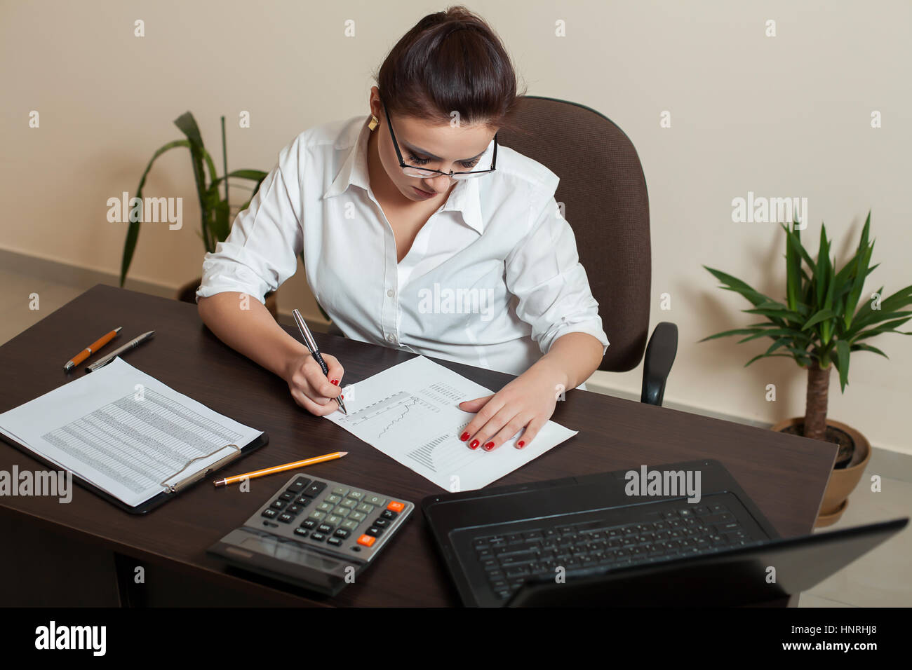 Female bookkeeper in glasses working at the table with laptop ...