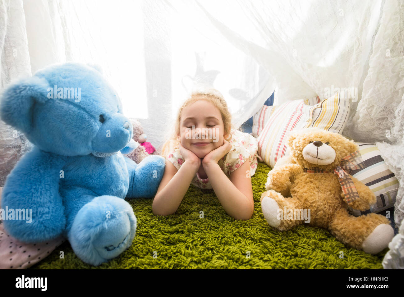 Little blonde child girl playing at home in her room with teddy bears Stock Photo