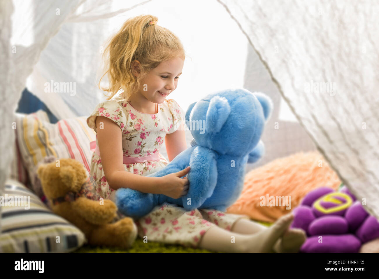 Little blonde child girl playing at home in her room with teddy bears Stock Photo