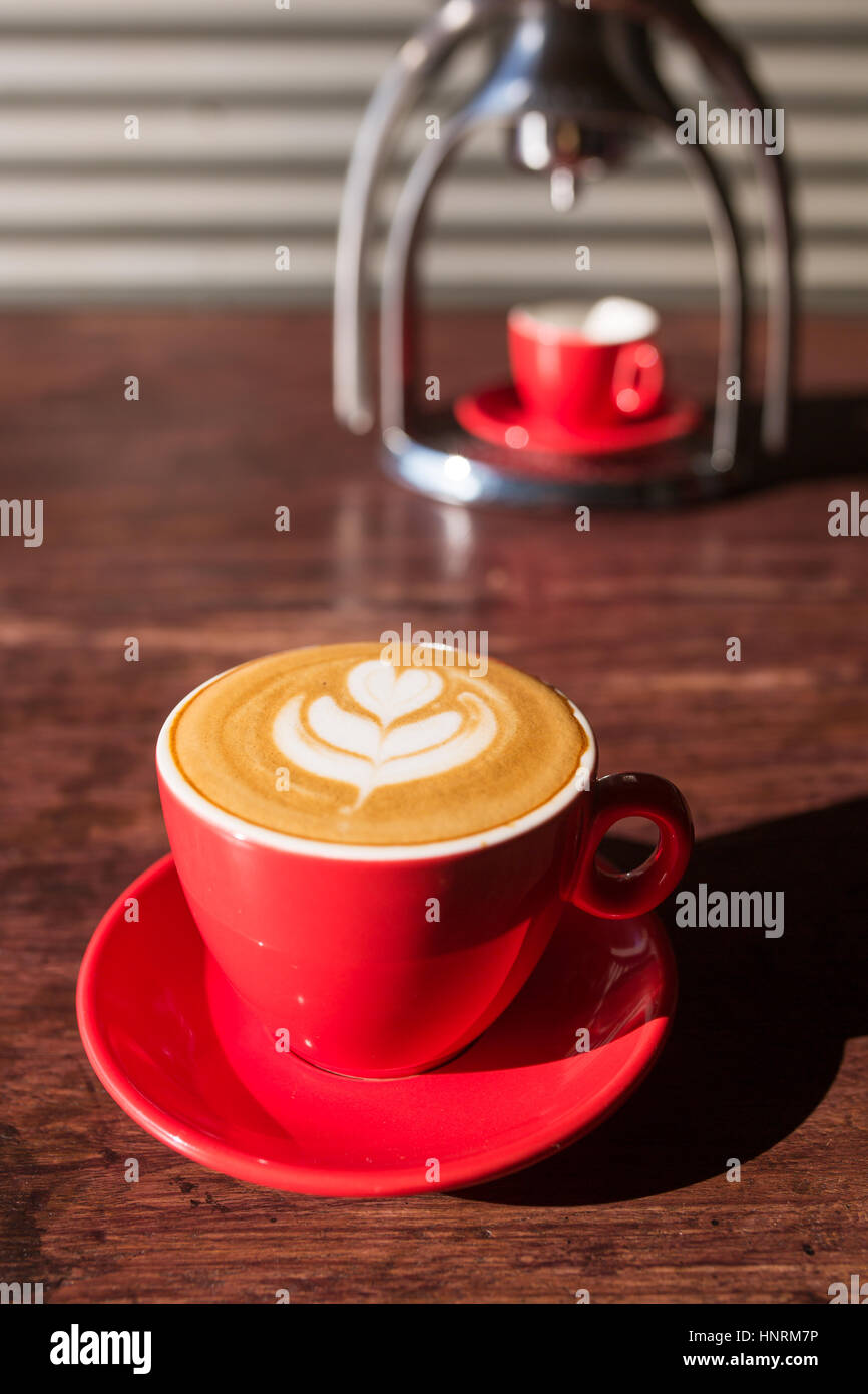 Manual old school espresso maker machine with a cup on wooden table in