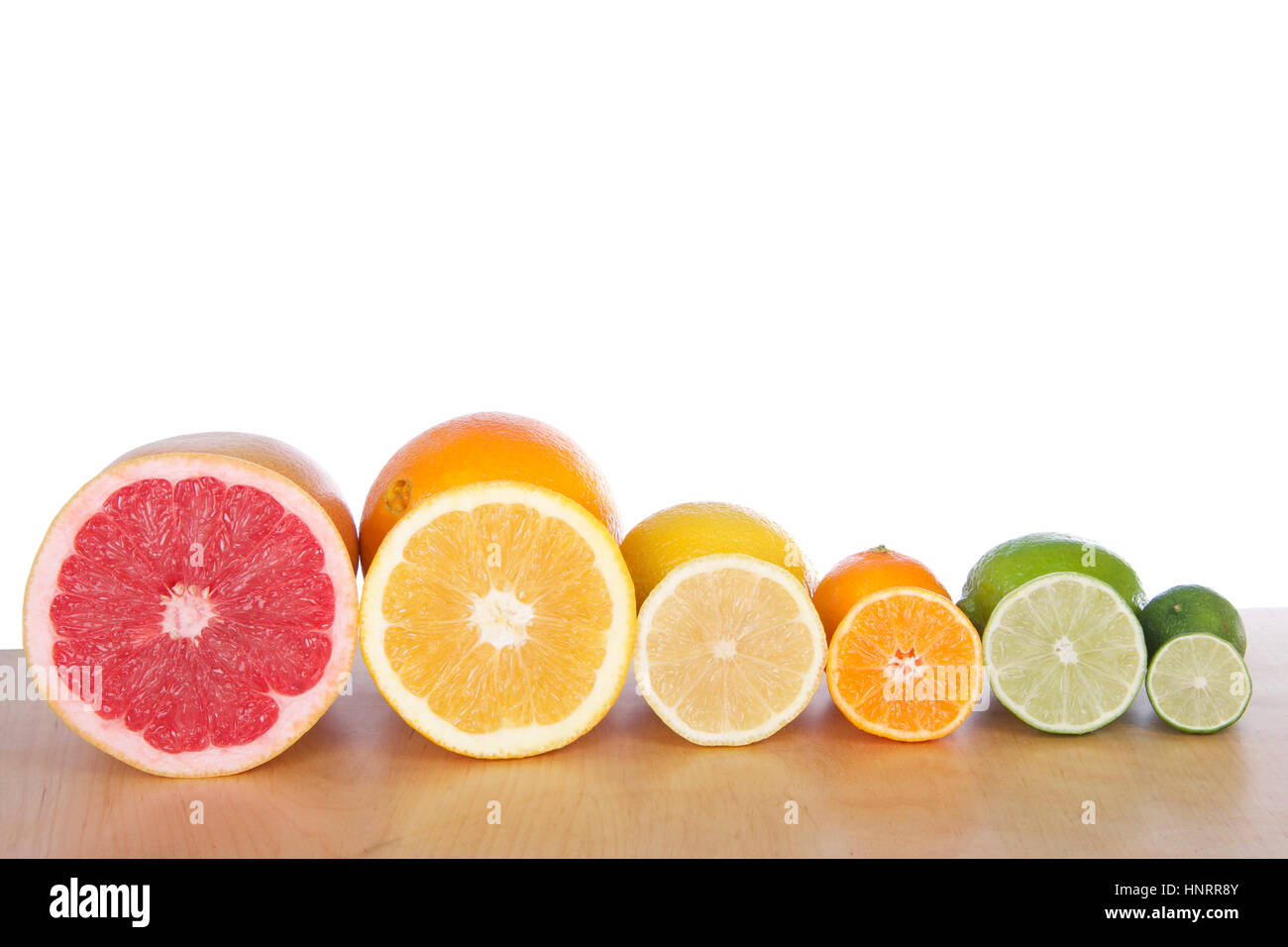 Colorful sliced citrus lined up in rows on a light brown wood table ...